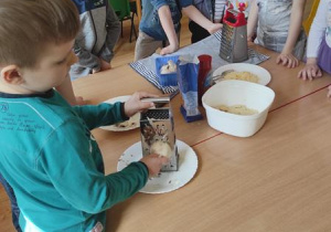Dzieci przygotowują składniki na pizzę.